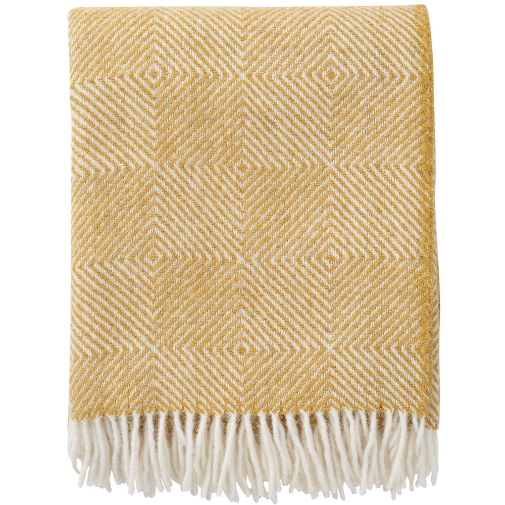 Yellow patterned throw blanket with white fringe on a white background
