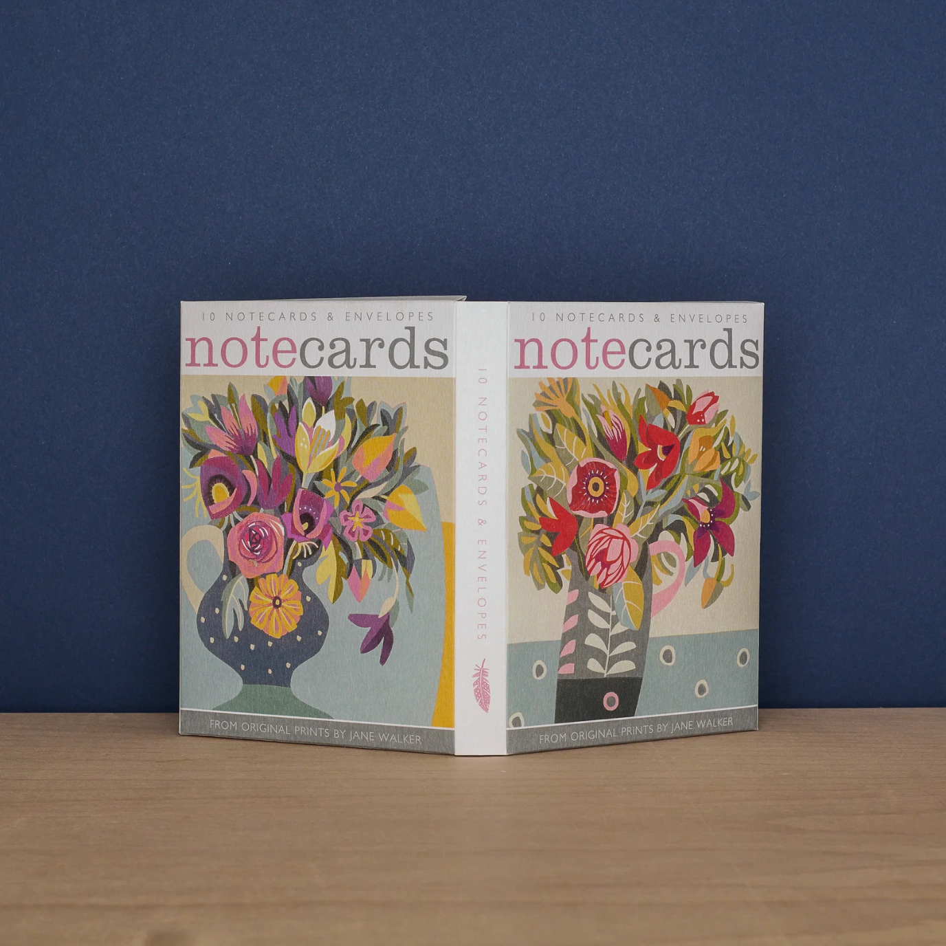 A fold-out box showing the designs inside - 2 different notecard designs of flowers in vessels in red, pink and purple tones. 