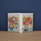 A fold-out box showing the designs inside - 2 different notecard designs of flowers in vessels in red, pink and purple tones. 