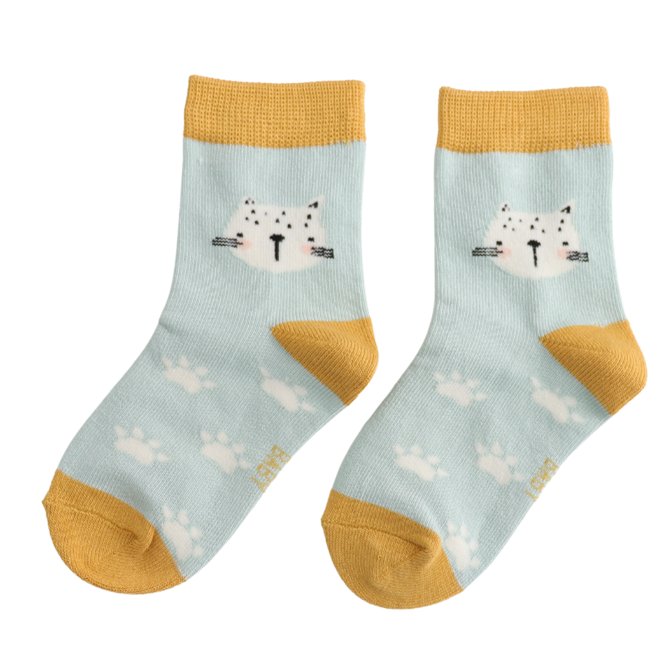 A pair of light blue crew socks with mustard yellow cuffs, heels, and toes, featuring a white cat face graphic on the top and small white paw prints scattered throughout. 