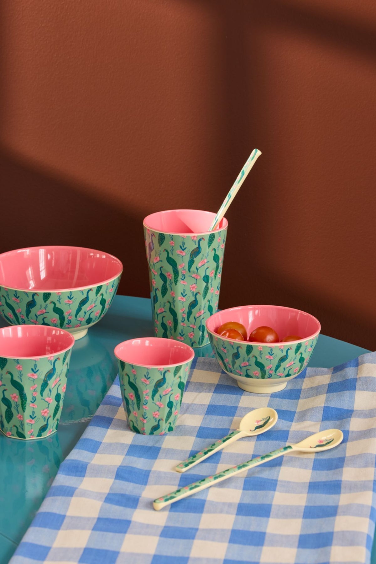 Set of colorful ceramic bowls and cups on a checkered tablecloth with a brown background