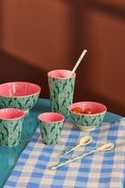 Set of colorful ceramic bowls and cups on a checkered tablecloth with a brown background