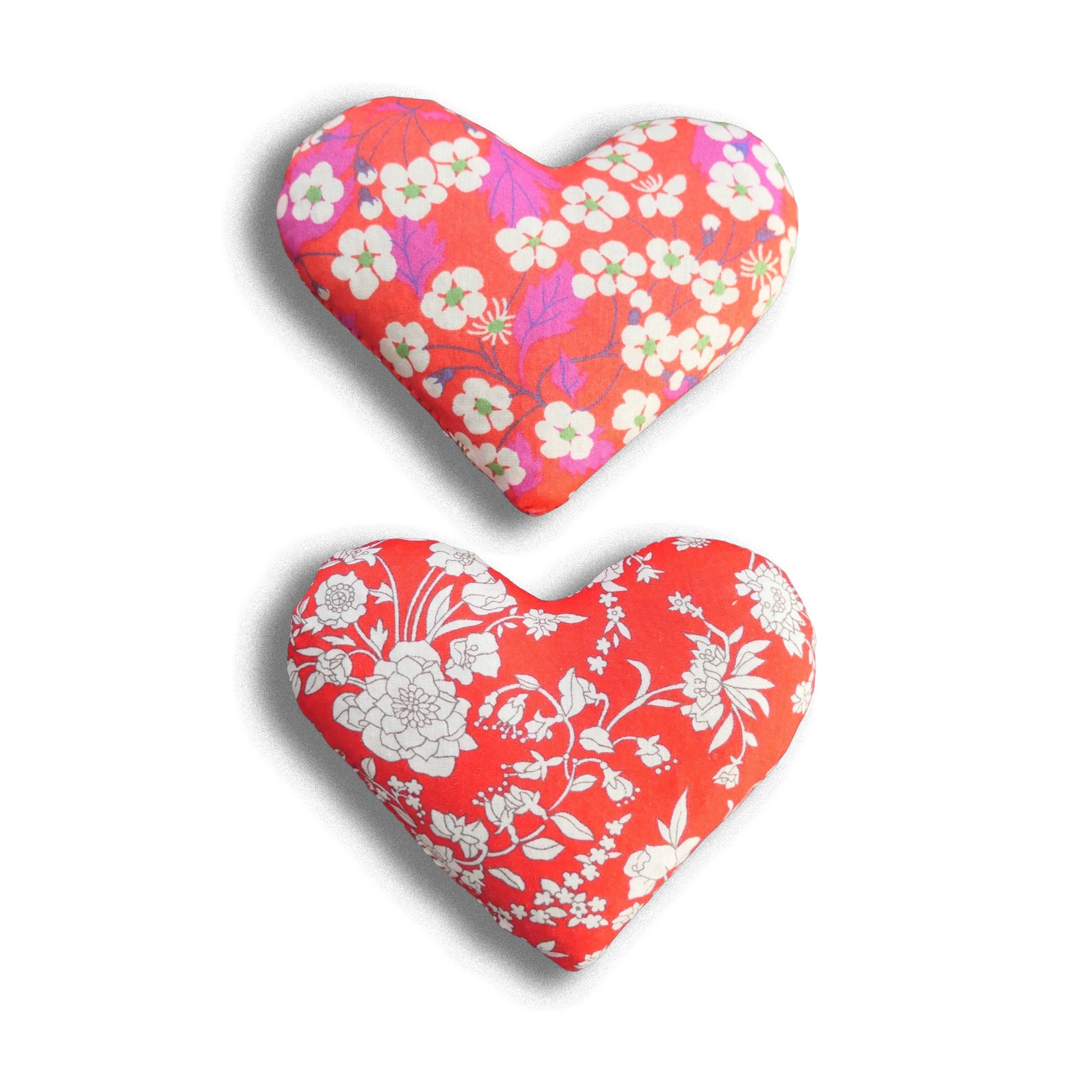 Two heart-shaped sachets in Liberty prints with pink and red floral patterns on a white background
