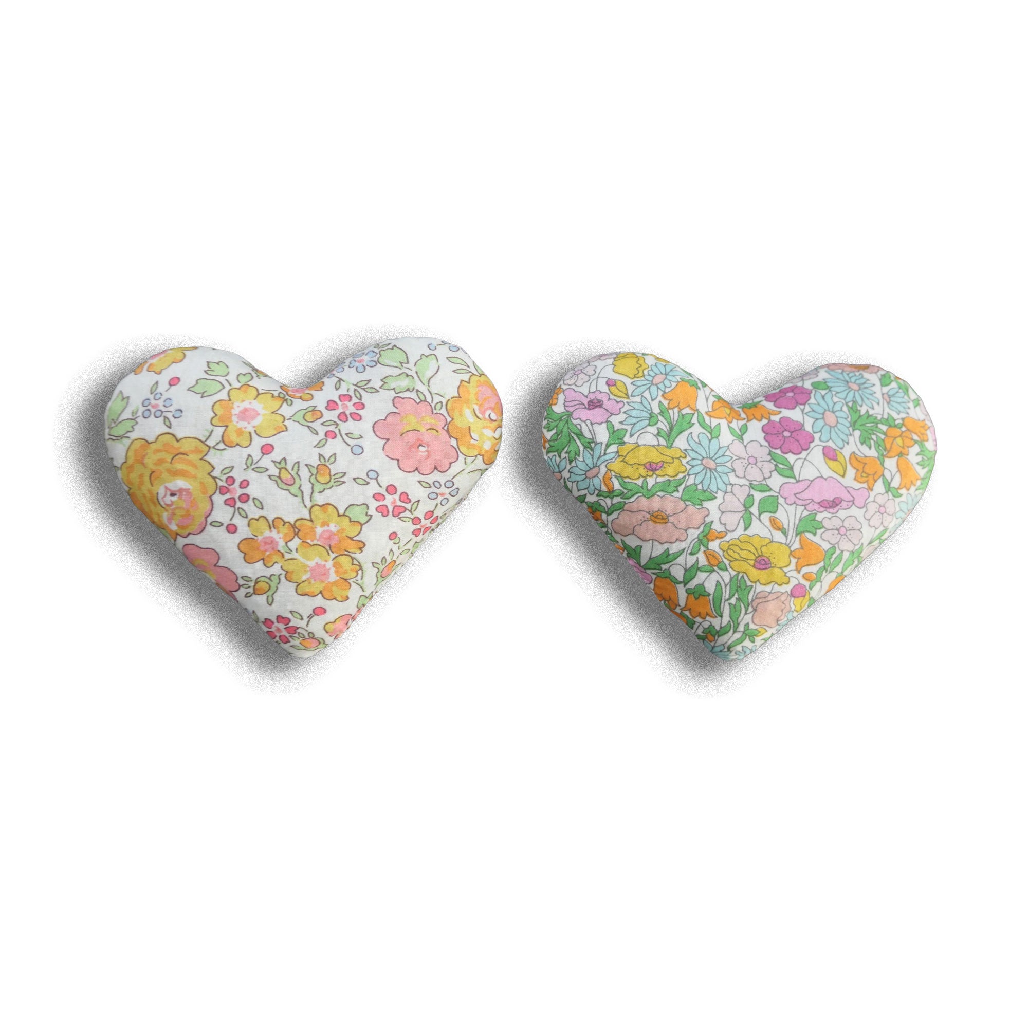 Two lavender heart sachets in yellow and orange floral patterns on a white background