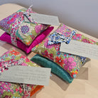Colourful floral-patterned fabric sachets on a wooden surface with tags.