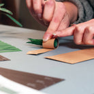 Person crafting with paper and green leaves on a light surface