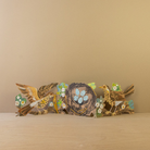 Decorative concertina card with birds and flowers on a wooden surface against a beige background