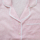 Pink pajama top with white trim on a light pink background