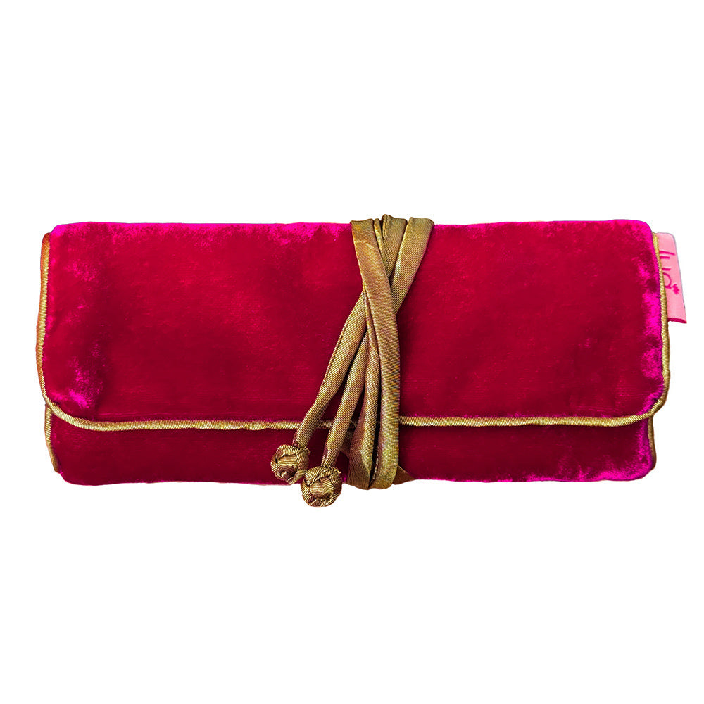 A bright magenta velvet clutch bag with gold trim and a gold rope tie closure, shown against a plain white background.