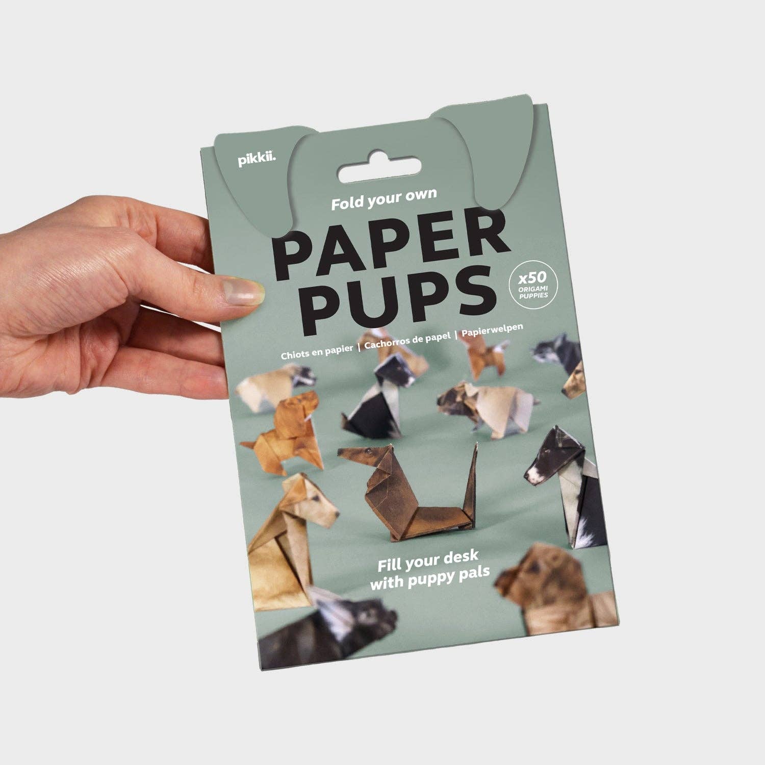 Rectangular packaging with dog ears and Pikkii branding. Features a picture of folded origami dogs. Reads “Fold your own paper pups” “x50 origami puppies” “Fill your desk with puppy pals”