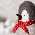 Stuffed penguin toy with a red polka dot bow on a blurred background