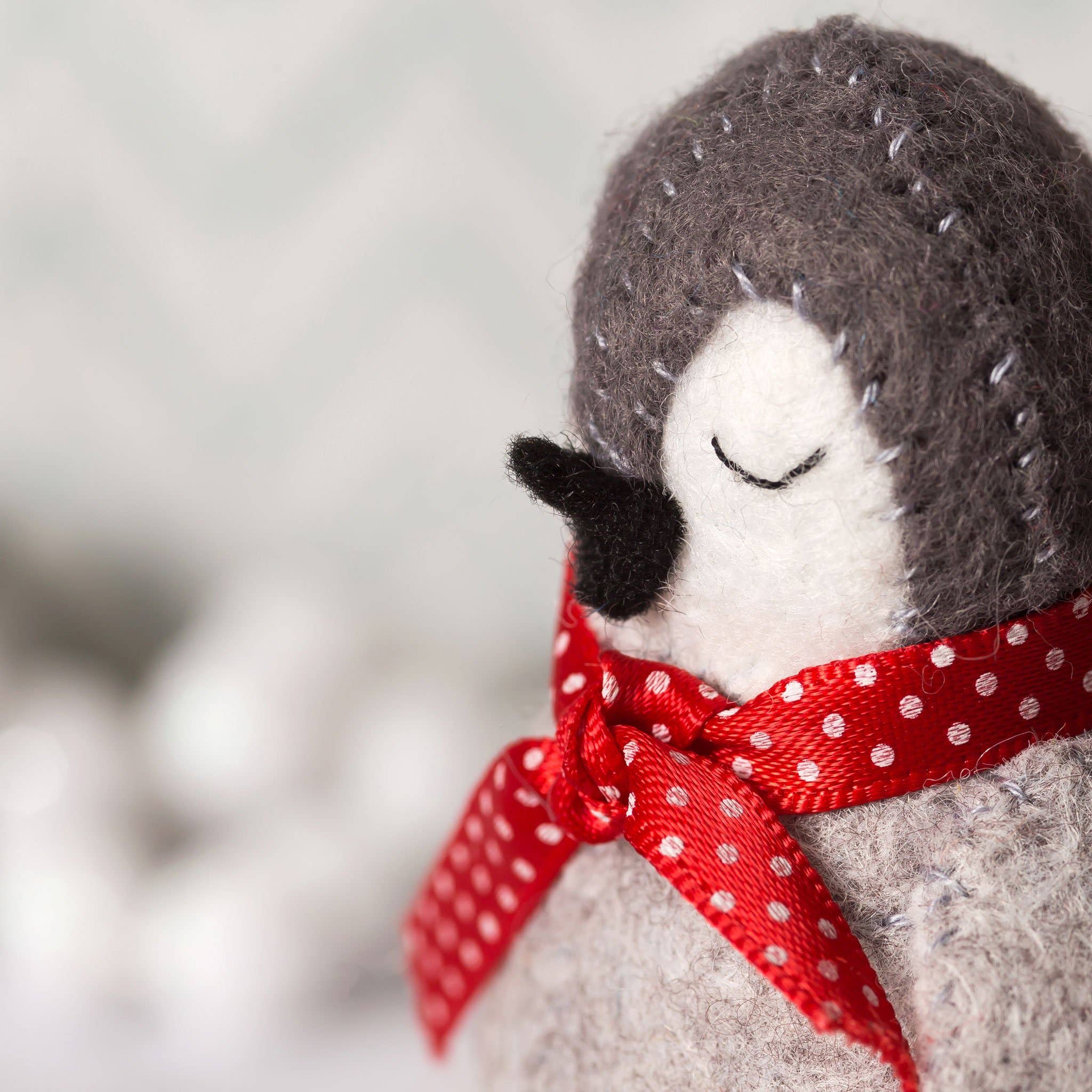 Stuffed penguin toy with a red polka dot bow on a blurred background