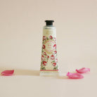 Hand cream bottle with floral design on a beige background