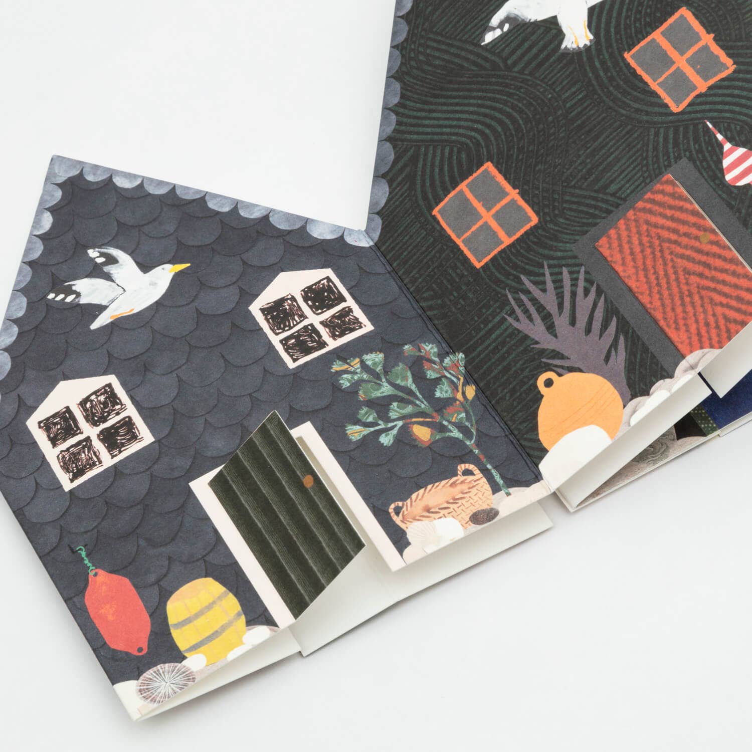 Notebook with a decorative cover featuring houses and birds on a white background