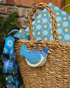 Wicker basket with a blue decorative bird tag against a patterned fabric background