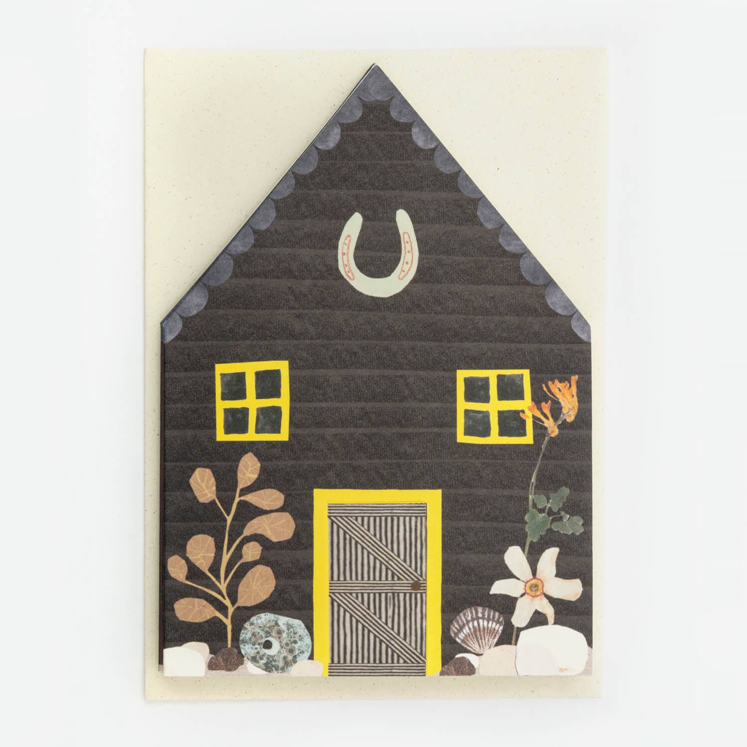 Decorative card with a house design featuring yellow windows and door, black shingles, and floral elements on a beige background.