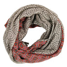 A lightweight infinity scarf with a dual-pattern design, featuring a gray and beige sunburst motif on one side and a red, pink, and gray oval pattern on the reverse, displayed on a clean white background.