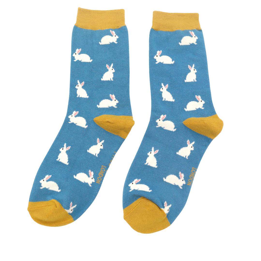 A pair of blue crew socks with a repeating pattern of white rabbits, featuring mustard yellow heels, toes, and ribbed cuffs, displayed on a solid white background.