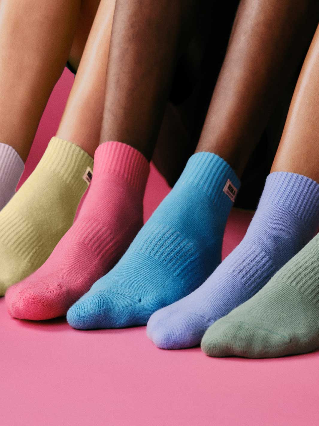 Five pairs of colorful socks on a pink background