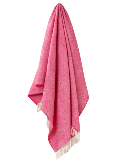 Pink throw blanket with white fringe on a beige background
