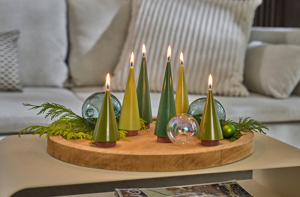Decorative candle set with green cone-shaped candles on a wooden base in a living room setting.
