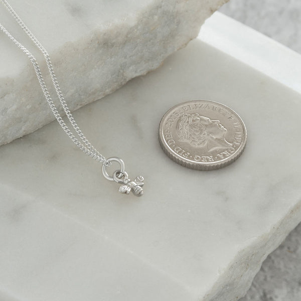 mini bee necklace next to 5p coin